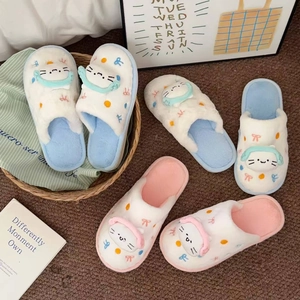 Détail de chaussons chat en peluche avec oreilles 3D et nœuds sur tapis douillet