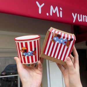 Close-up of ceramic dog mug in hands with red striped patterns and matching gift box