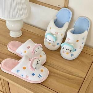 Détail de chaussons chat en peluche avec têtes 3D et texture douce en polaire corail