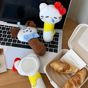 Detail view of cute plush Hello Kitty and puppy handheld mirrors on a wooden desk