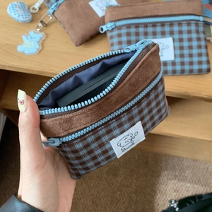 Detail of suede and plaid patchwork card pouch with a cute cartoon dog label and zipper