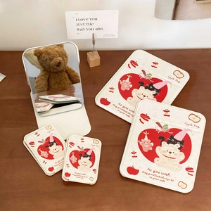 Macro detail of cute apple bear folding mirrors and pouches on a warm wooden desk