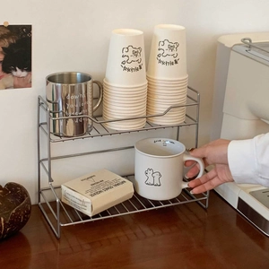 Nahaufnahme eines zweistufigen Silber-Edelstahlregals für Kaffeetassen und Deko