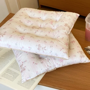 Close-up of square floral seat cushion with rabbit patterns and decorative wavy edges