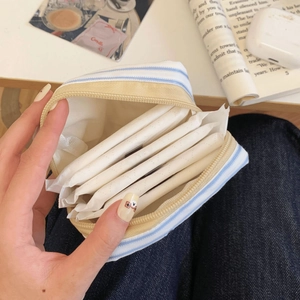 Close-up of blue striped fabric storage pouch with sanitary pads in a lifestyle setting