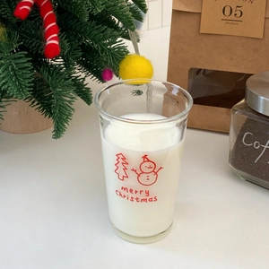 Detail of Christmas snowman glass cup filled with milk showing festive tree and text print