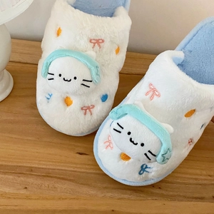 Gros plan de chaussons en peluche chat avec détails de casque et broderies colorées