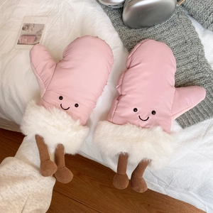 Pink cartoon skiing mittens with plush fur trim and cute 3D feet on a soft white bed
