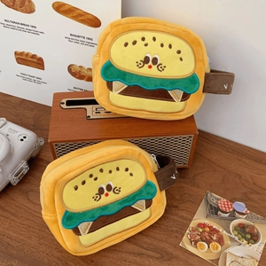 Plush burger-shaped camera pouch with cute embroidery on a vintage wooden tabletop