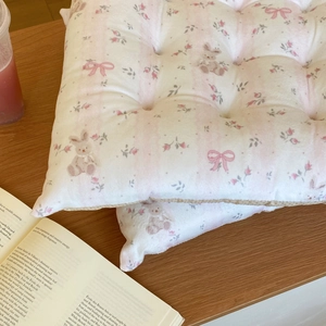 Detail of floral quilted seat cushions with pink roses and rabbit patterns on a wood desk