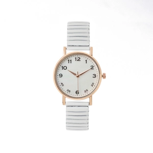 Detail of rose gold round watch case with white elastic strap and clear numerals