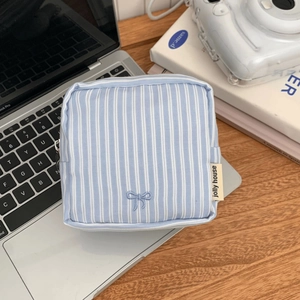 Detailed close-up of blue striped storage pouch with embroidered bow on laptop