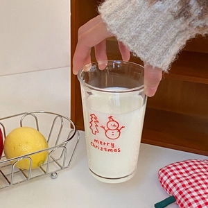 Close-up of glass milk cup with red Christmas snowman pattern and Merry Christmas text