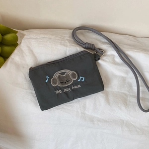 Detail view of dark grey pouch with cartoon bear embroidery and adjustable lanyard