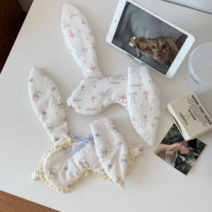 Detail of cute rabbit ear sleep masks with lace trim and angel prints on a white desk