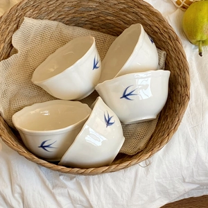Dettaglio di cinque ciotole in ceramica con motivi a rondine blu e bordo a onde