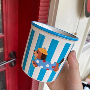 Detail of striped ceramic dog mug showing vertical blue lines and cartoon dachshund illustration