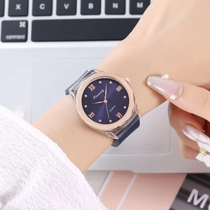 Close-up of rose gold octagonal watch with blue sunray dial and grey silicone strap