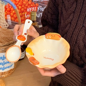 Detail of a ceramic bowl and spoon set featuring embossed food design and Yummy text
