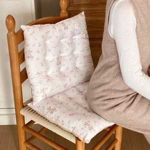 Close-up of floral chair cushion with cute rabbit and bow patterns on wooden seat