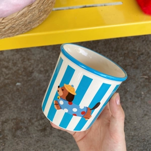 Close-up of blue striped ceramic mug featuring a cute dachshund in polka dot clothes
