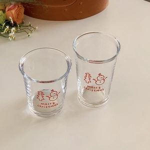 Close-up of Christmas glass cups with snowman and tree prints in a cozy festive setting