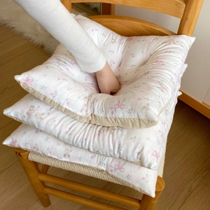 Floral print square chair cushions with rabbit patterns on a woven wooden chair