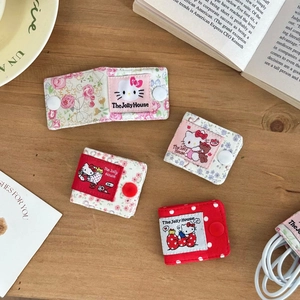 Detail of floral fabric cable organizers with cute cat motifs on a wooden surface