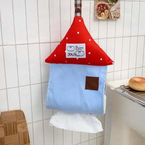 Hanging house-shaped tissue box with polka dots on a tiled wall in a cozy room