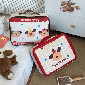Detail of cute cartoon puppy travel storage bags with red handles on a white bed