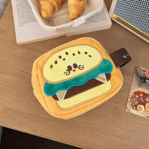 Detail of cute burger-shaped plush camera bag with embroidery on a wooden table