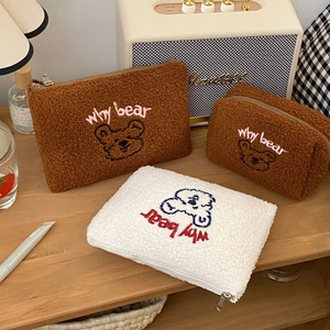Close-up of teddy bear embroidery and fuzzy fleece texture on cute storage makeup bags