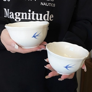Dettaglio della ciotola in ceramica bianca con motivi a rondine blu e bordi ondulati