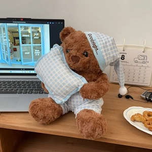Detailed close-up of brown plush teddy bear wearing blue checkered sleepwear and a nightcap