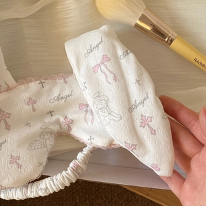 Close-up of cute white sleeping eye mask with pink lace edges and angel print