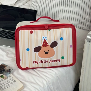 Detail of cartoon puppy travel bag on bed showing fabric texture and red handle
