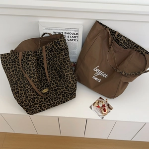 Chic leopard print and brown canvas tote bags displayed on a minimalist white shelf