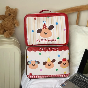 Detail of cartoon puppy travel storage bags with zippers and handles on a bed