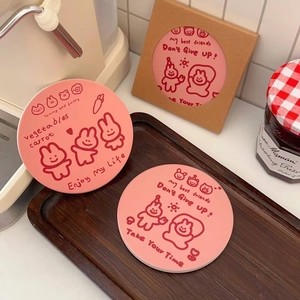 Close-up of pink round ceramic coaster with cute cartoon rabbit and inspirational quotes
