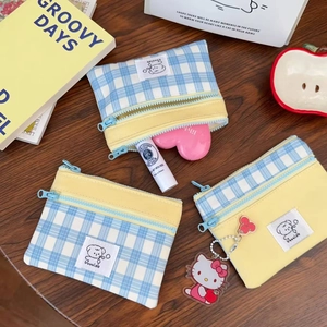 Detail of checkered zip pouch with cute cartoon patch on a cozy desktop setup