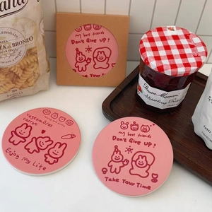 Detail of pink ceramic coasters with cute cartoon rabbit prints and uplifting slogans