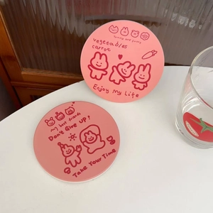 Close-up of pink round cartoon rabbit ceramic coasters with inspirational quotes on desk