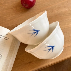 Ciotole in ceramica minimaliste con motivo a rondine e bordi ondulati su tavolo legno