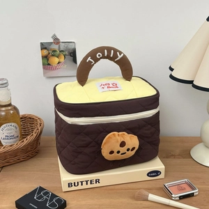 Close-up of quilted cosmetic bag with plush biscuit doll and embroidered handle