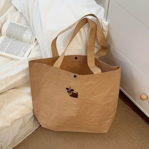 Close-up of brown kraft paper tote bag with cute cartoon puppy embroidery and snap button