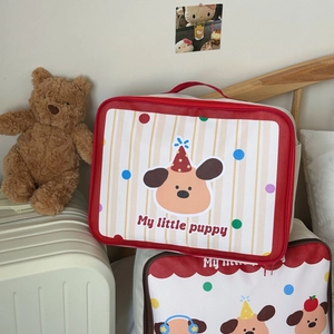 Detail of red cartoon puppy storage bags with zipper and handle against a suitcase