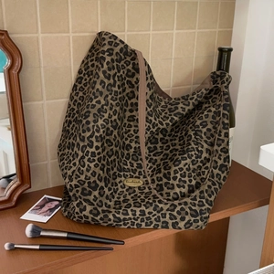 Detail of leopard print canvas tote bag featuring an oval handmade gold metal plaque