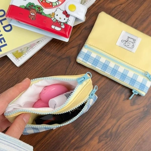Detail of yellow and blue plaid canvas storage bag holding earphones and lipstick