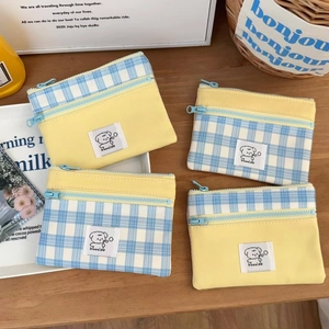 Detail of yellow and plaid zipper pouch with cute cartoon dog label on wooden table