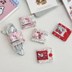Detailed view of floral Hello Kitty cable organizers with snap buttons on white desk